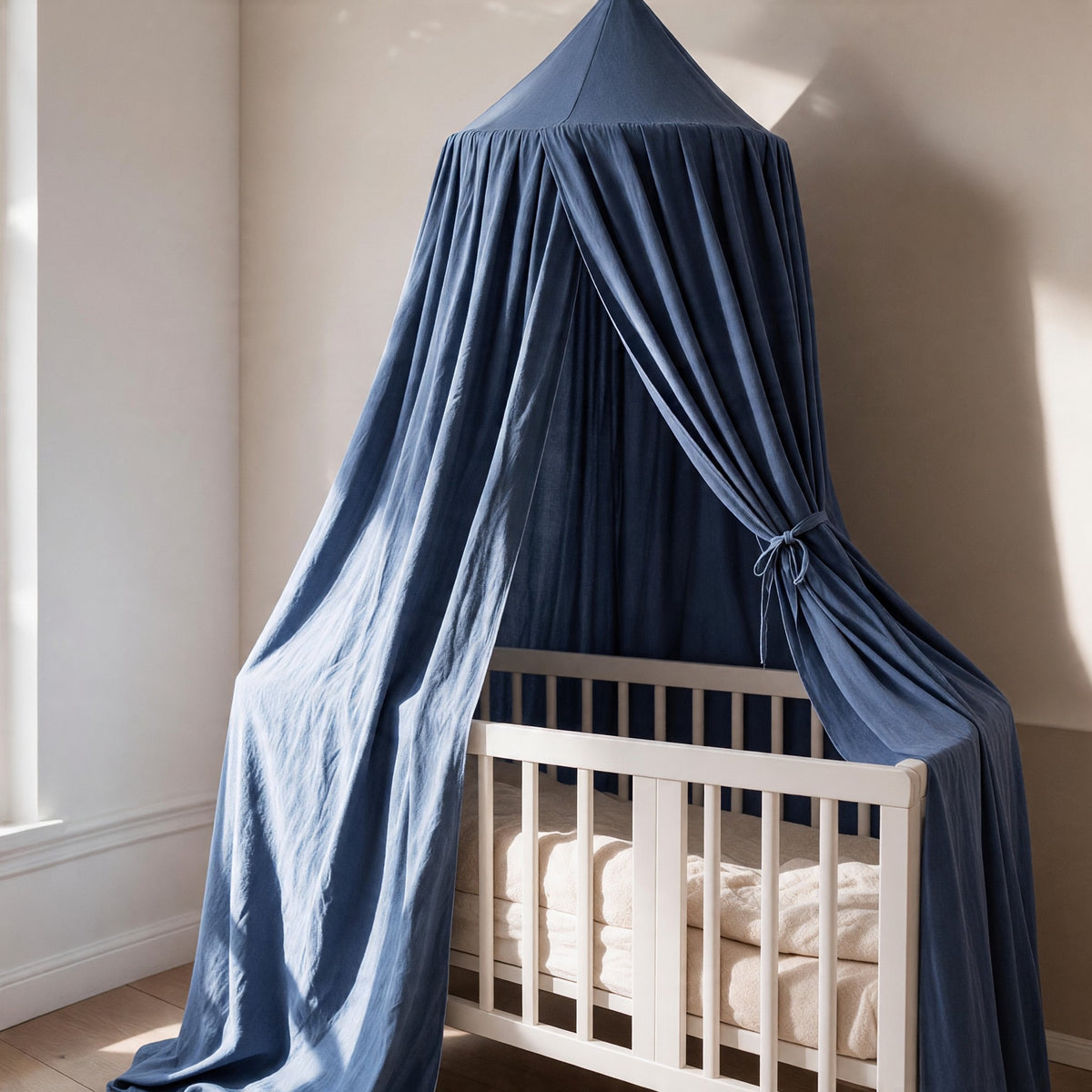 Ciel de lit bébé bleu jean Indigo au-dessus d'un berceau blanc