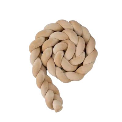 Contour de lit bébé beige roulé en spirale, velours doux et sécurisant.
