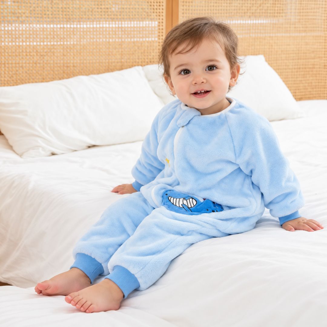Enfant assis sur le lit en gigoteuse pyjama à jambes bleu ciel