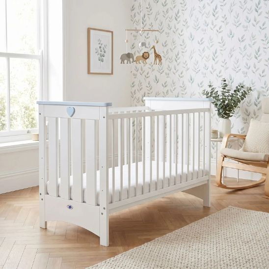 Lit bébé à barreau blanc dans une chambre naturelle avec décoration douce