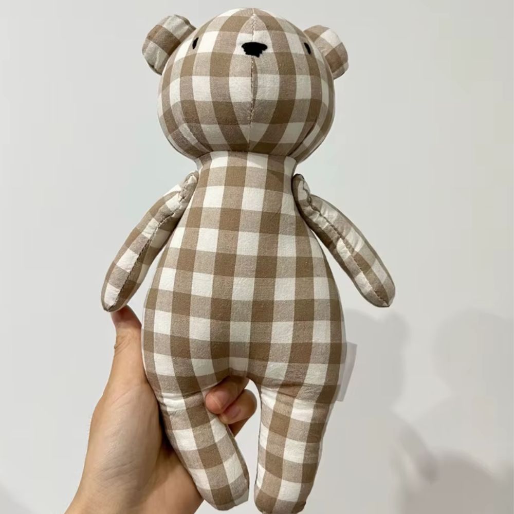 une main tenant l'ourson en peluche en position de face