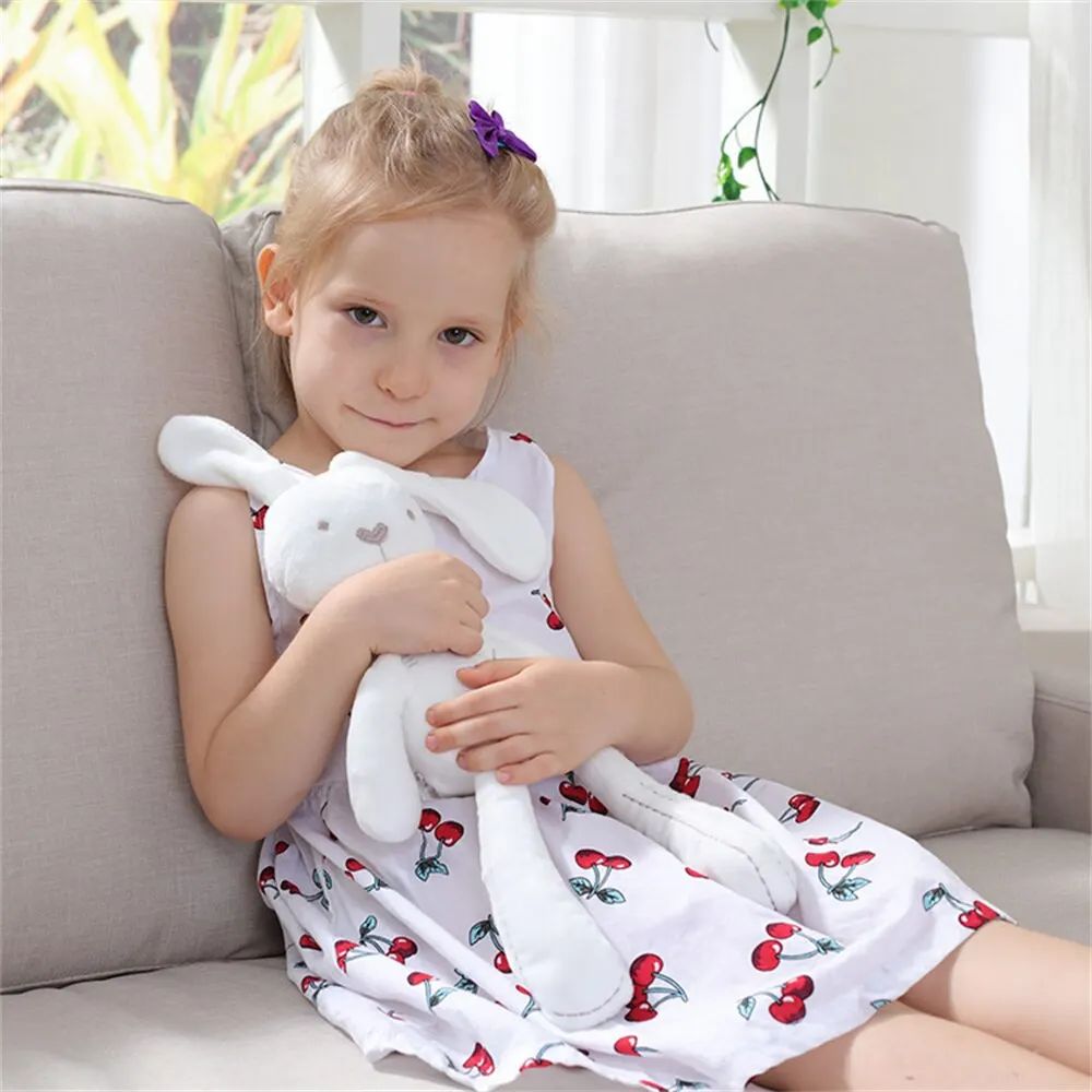 Bébé jouant avec une peluche lapin blanc confortablement installé