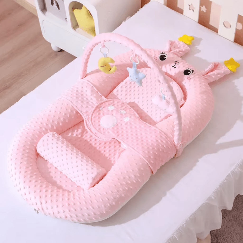 Réducteur de lit – coussin anti-reflux rose poudré, ambiance chambre bébé, cocon minky avec arche d’éveil.
