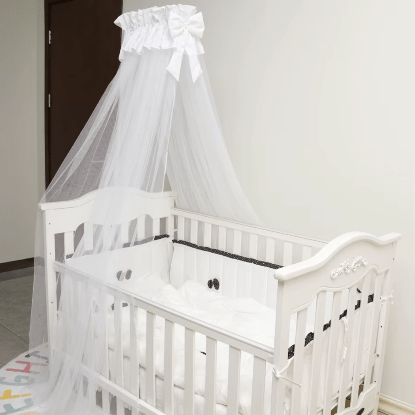 Décoration de chambre bébé avec tour de lit blanc élégant et moustiquaire fine.