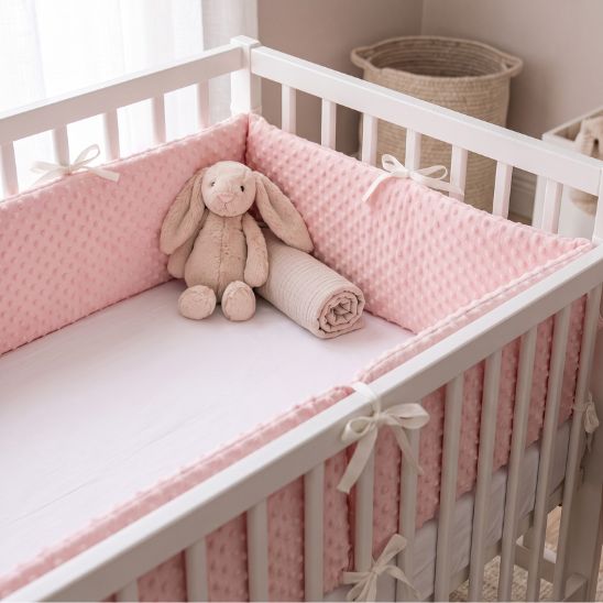 Tour de lit bébé rose à pois en relief installé dans un berceau blanc