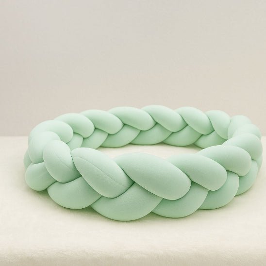 Tour de lit bébé tressé vert d’eau, accessoire décoratif et protecteur pour chambre de bébé.