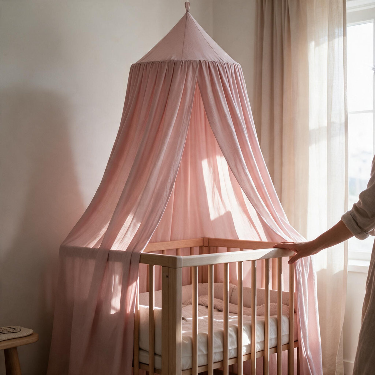 Ciel de lit bébé Rêverie rose poudré suspendu au-dessus d'un berceau en bois