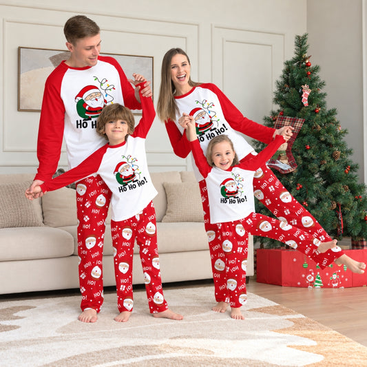 Famille en pyjama Noël famille Père Noël Guirlande rouge et blanc devant le sapin