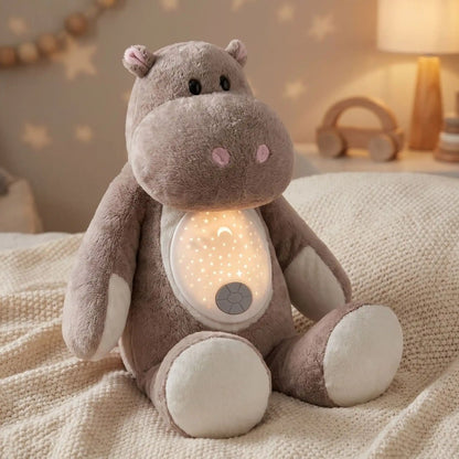 Peluche hippopotame Hippolyte avec son dôme projecteur allumé sur un plaid crème