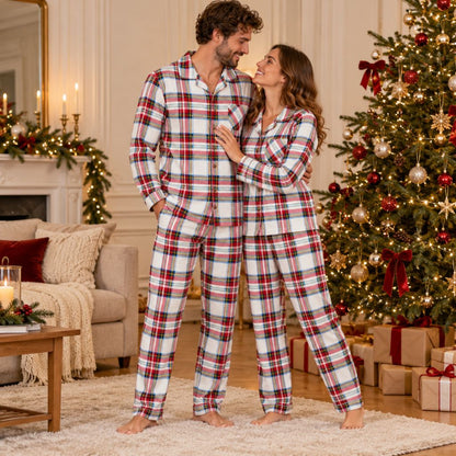 Couple en pyjama de Noël tartan blanc rouge et marine devant le sapin