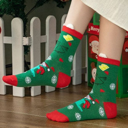 Chaussettes de Noël vertes à flocons portées devant une barrière blanche