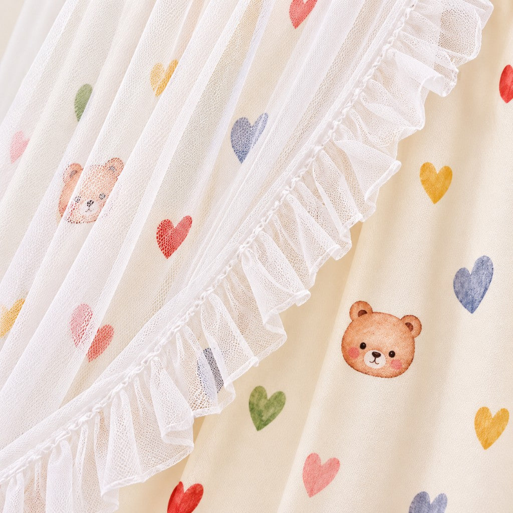 Détail du tissu imprimé cœurs et oursons sous le tulle à volants du ciel de lit enfant