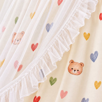 Détail du tissu imprimé cœurs et oursons sous le tulle à volants du ciel de lit enfant