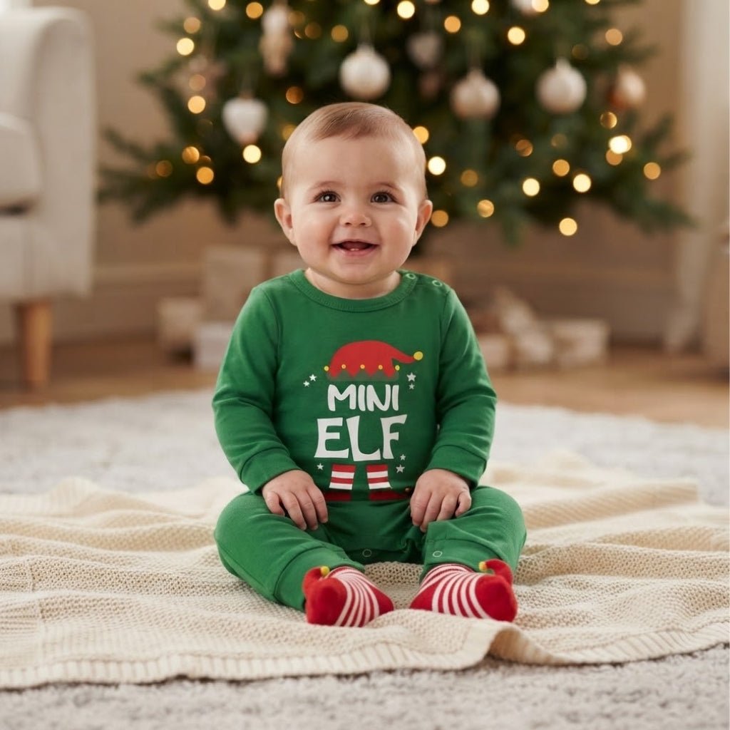 Bébé en grenouillère de Noël verte Mini Elf assis sur une couverture