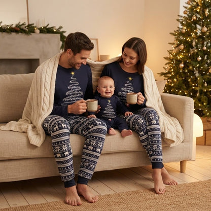 Parents et bébé en pyjama de Noël bleu marine assortis sur le canapé