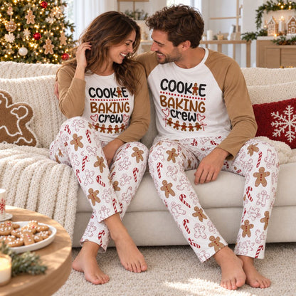 Couple en pyjama Noël assorti pain d'épice sur le canapé devant le sapin