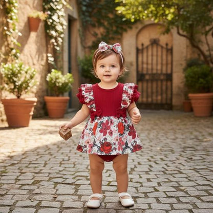 Barboteuse bébé fille robe florale rouge bébé debout dans cour pavée