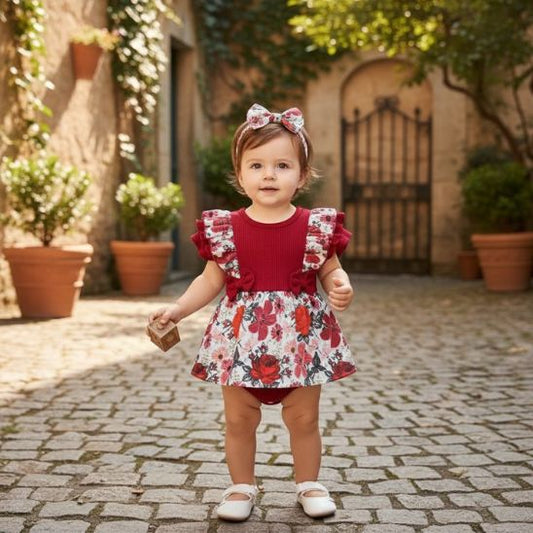 Barboteuse bébé fille robe florale rouge bébé debout dans cour pavée
