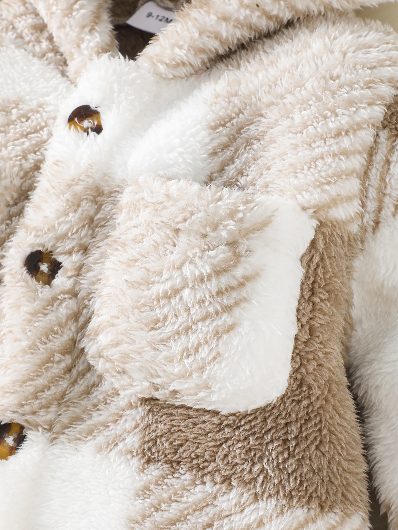 Zoom sur le tissu peluche doux de la barboteuse bébé beige sable