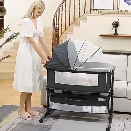 Bébé endormi dans un berceau à roulettes 3 en 1 noir avec moustiquaire fermée.