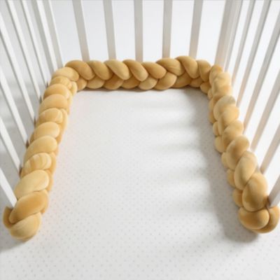 Contour de lit bébé tressé camel en velours installé dans un berceau blanc