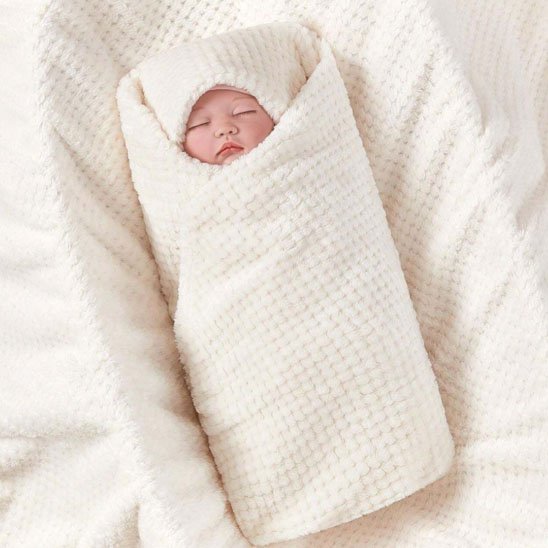 Enfant blotti dans une couverture bébé blanche douce et moelleuse