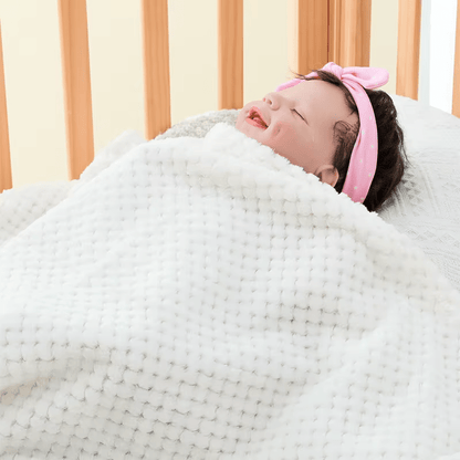 Bébé dormant paisiblement sous une couverture bébé blanche