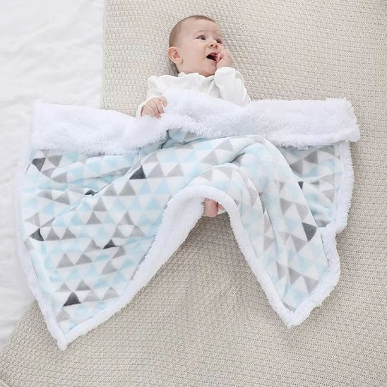 Bébé couché sur couverture bébé douillette motif triangles