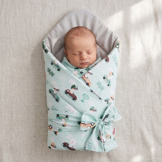 Bébé emmailloté dans une couverture motif lapins pilotes de course, intérieur gris