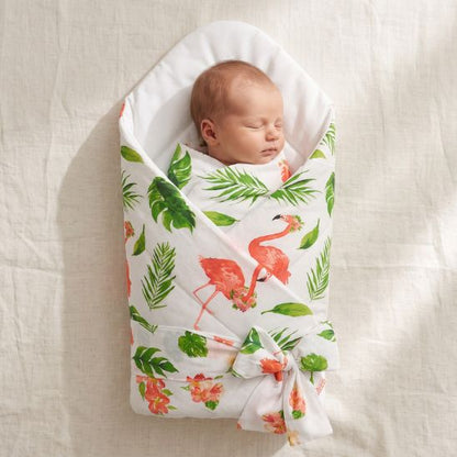 Bébé emmailloté dans une couverture motif flamants roses et feuillage tropical