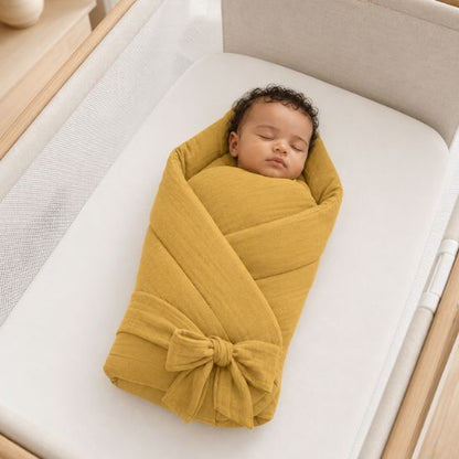 Bébé emmailloté dans une couverture d'emmaillotage moutarde en mousseline de coton, allongé dans un lit à barreaux