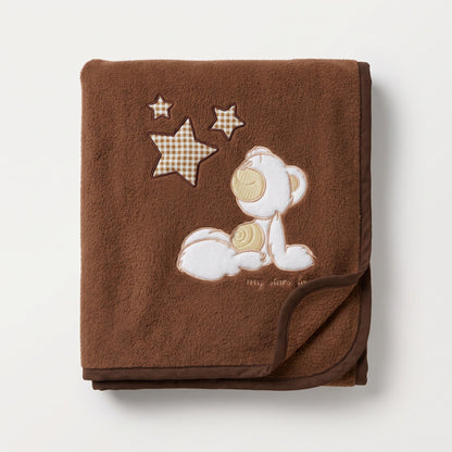 Couverture en polaire bébé marron avec ourson brodé, pliée dans un couffin en osier
