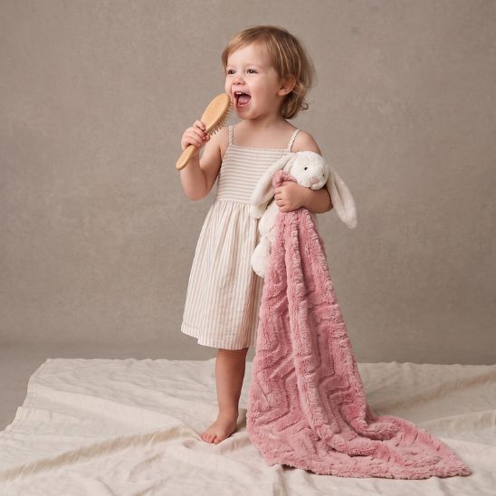 Petite fille tenant son doudou lapin et la couverture lit bébé rose pendant un moment d'éveil