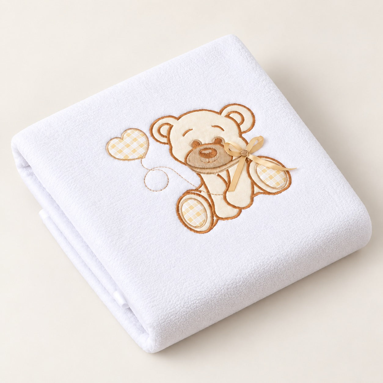 Couverture en polaire bébé coloris blanc avec ourson et cœur brodés, pliée