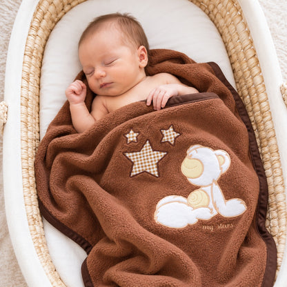 Nouveau-né endormi dans un couffin, enveloppé dans une couverture en polaire marron avec ourson brodé
