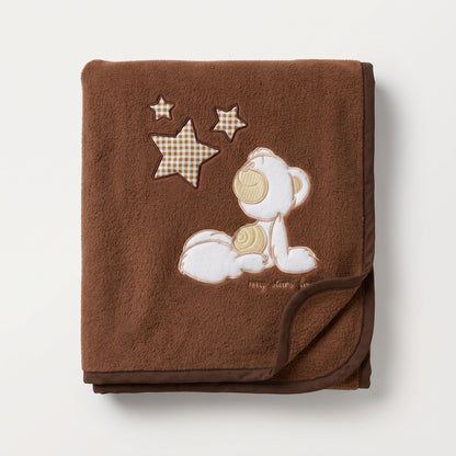 Couverture en polaire bébé marron avec ourson brodé, pliée dans un couffin en osier