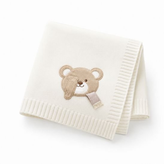 Couverture tricot pour bébé blanc écru avec ourson brodé, pliée