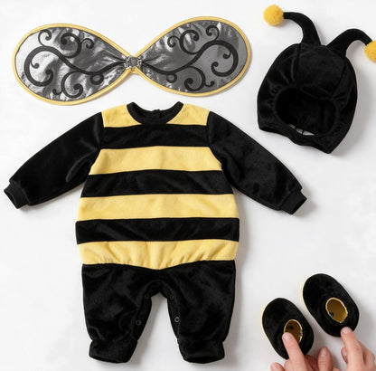 Bébé en déguisement abeille vu de dos qui se retourne en souriant, ailes argentées bien visibles