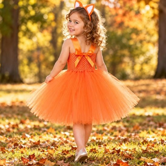 Dos du déguisement renard avec bretelles en satin croisées et nœud orange, porté par une petite fille qui se retourne en souriant