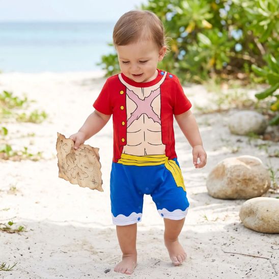 Bébé en déguisement pirate tenant une carte lors d’une aventure sur la plage