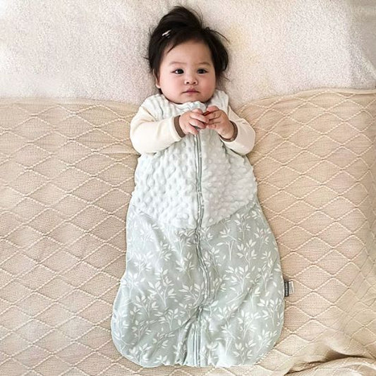 Gigoteuse sans manches bi-matière mi-saison, bébé allongé, zip central, haut matelassé blanc et bas vert sauge à motifs.