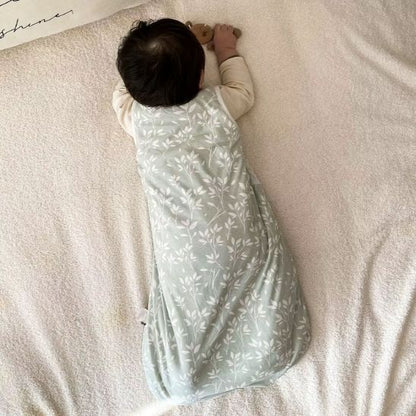 Dos de la gigoteuse sans manches bi-matière, motif feuillage vert sauge, bébé allongé sur le ventre.