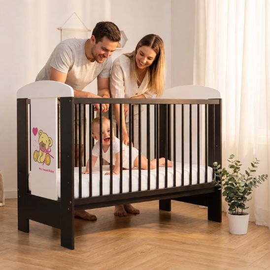 Parents souriants regardant leur bébé dans un lit à barreau bébé décor ourson wengé