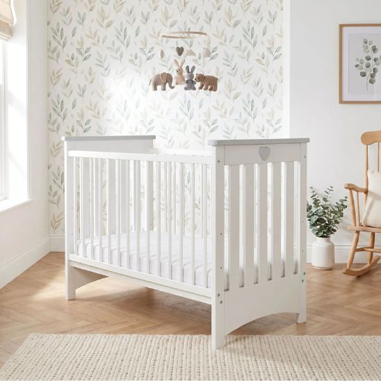 Lit bébé à barreau blanc avec mobile bébé en bois et chambre apaisante