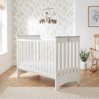 Lit bébé à barreau blanc avec mobile bébé en bois et chambre apaisante