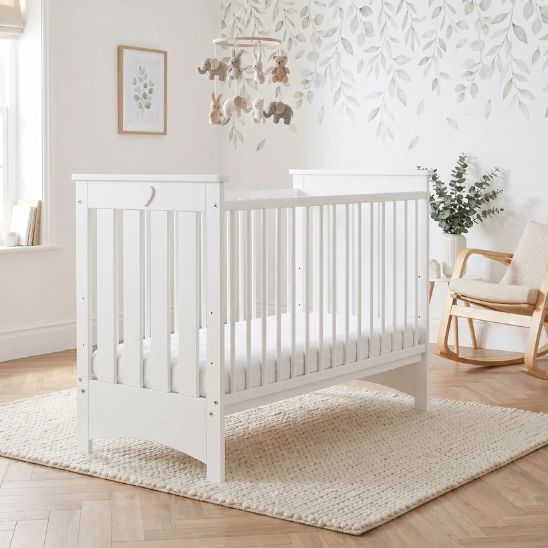Lit bébé à barreau blanc dans une chambre bébé avec décoration feuillage