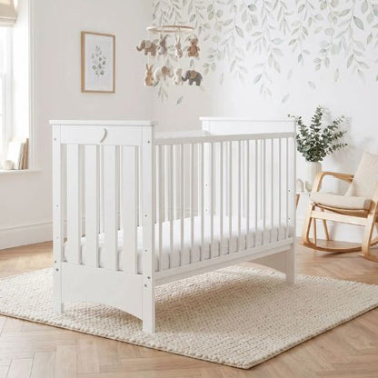 Lit bébé à barreau blanc dans une chambre bébé avec décoration feuillage