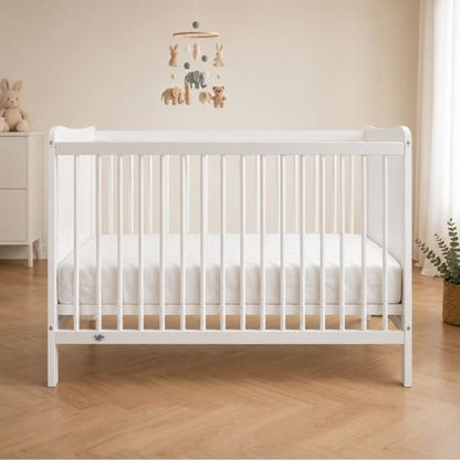 Lit bébé blanc dans une chambre unisexe beige avec mobile animaux en bois