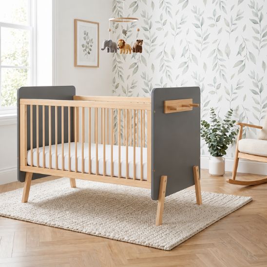 Lit bébé évolutif bois naturel et gris dans une chambre avec papier peint feuilles et mobile animaux