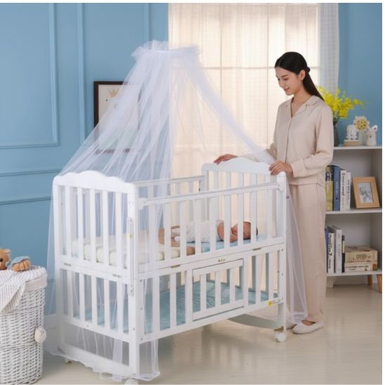 Lit moustiquaire bebe Spot Céleste blanc uni maman qui installe le baldaquin sur berceau
